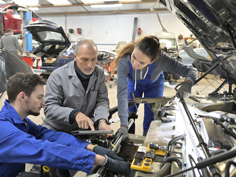 Instructor with trainees working on car engine